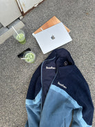 Flat lay of the reversible Buchan fleece in blue with drinks and a laptop, showing both sides