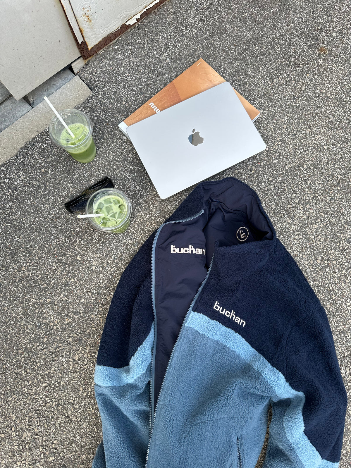 Flat lay of the reversible Buchan fleece in blue with drinks and a laptop, showing both sides