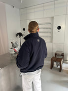 Back view of a model wearing the reversible Buchan fleece in blue on the navy nylon side, collar up
