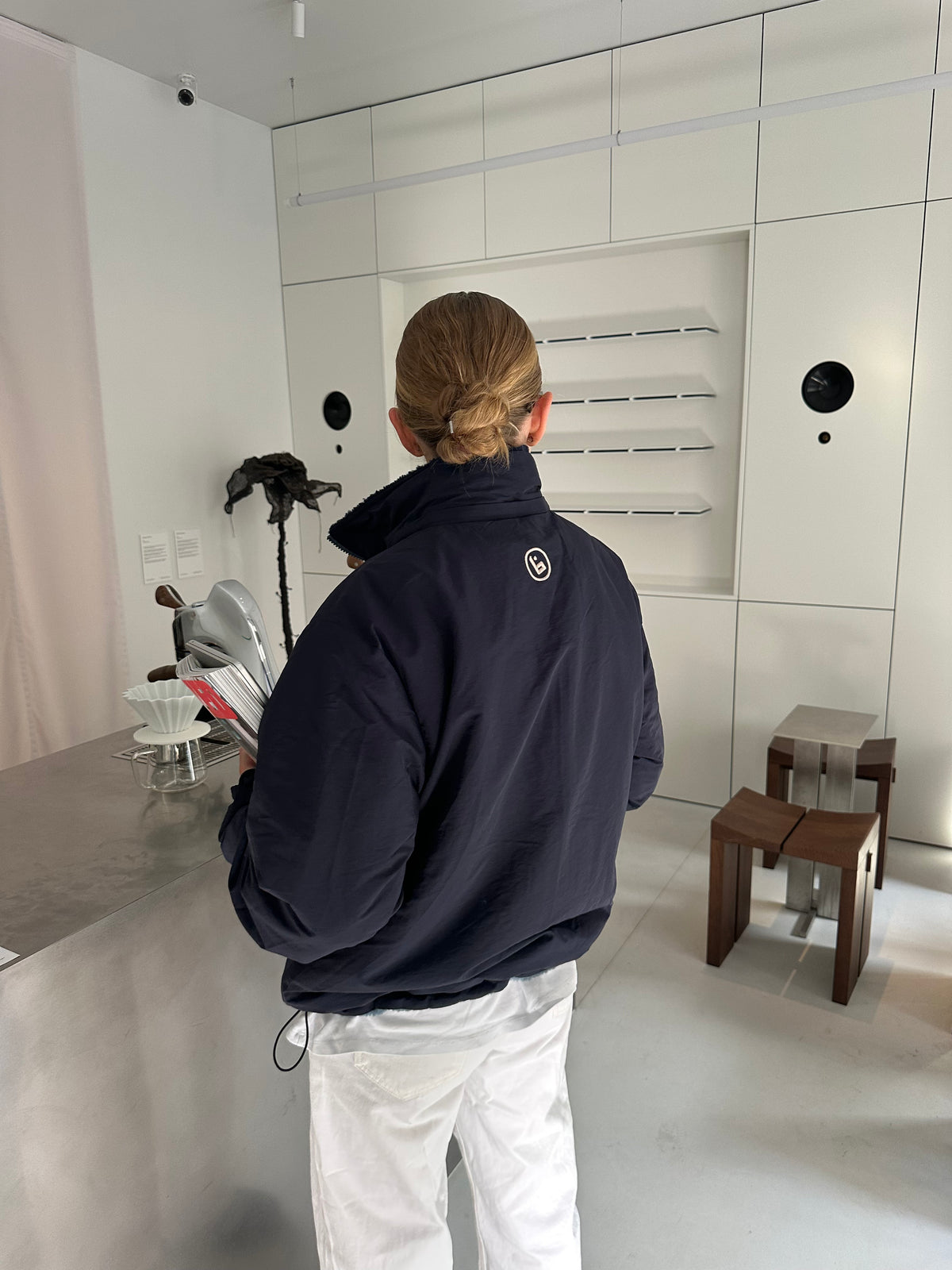Back view of a model wearing the reversible Buchan fleece in blue on the navy nylon side, collar up