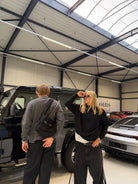 Two models in a car showroom, one carrying the Buchan small cargo bag in black across the chest