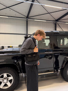 Model in a car showroom wearing the Buchan small cargo bag in black across the body