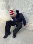 Model sitting on a kerb in the reversible Buchan fleece in blue, navy nylon side out with the hood up