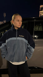 Model at night wearing the reversible Buchan fleece in blue, navy and blue sherpa zipped to the collar