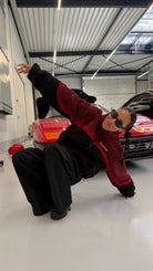 Model striking a pose in a car garage wearing the reversible Buchan fleece in red