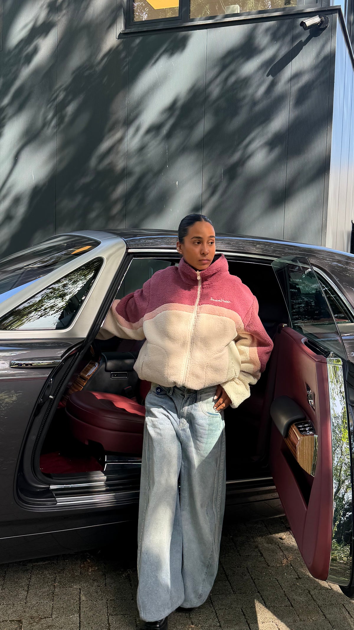 Model stepping out of a car in the reversible Buchan fleece in pink with wide-leg jeans