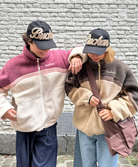 Two models wearing the reversible Buchan fleece in brown, fleece side out, against a white brick wall